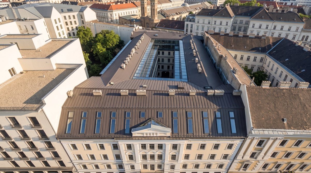 Az épület felülnézetből, tetőablakokkal; a háttérben a Dohány utcai zsinagóga kupolái.